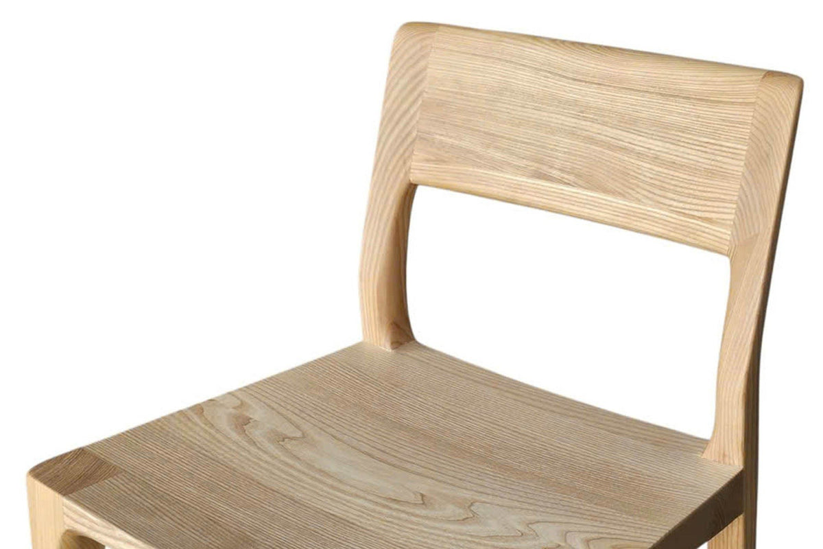 Close-up of the Cison seat in Natural: a dished solid ash seat with the end grain of the front legs at its corners