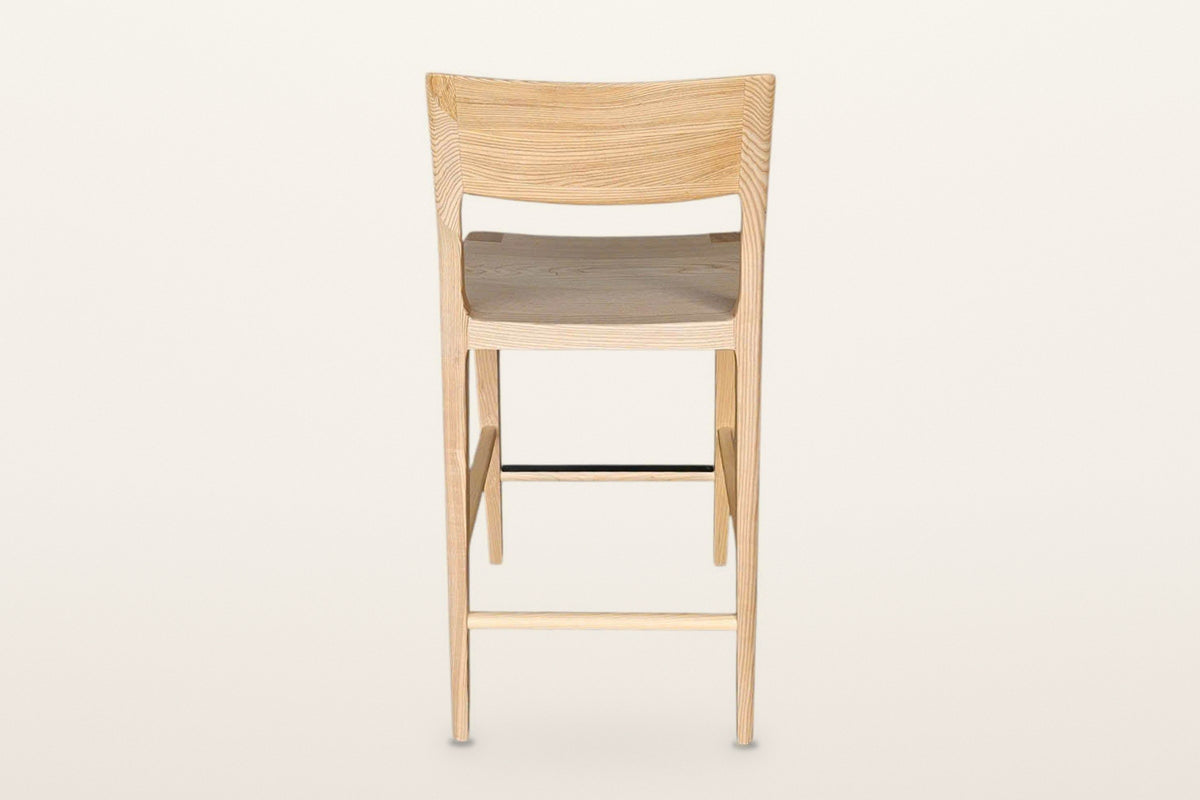 Cison counter stool in Natural from behind on a warm white studio backdrop: the outer face of the curved backrest and the rou