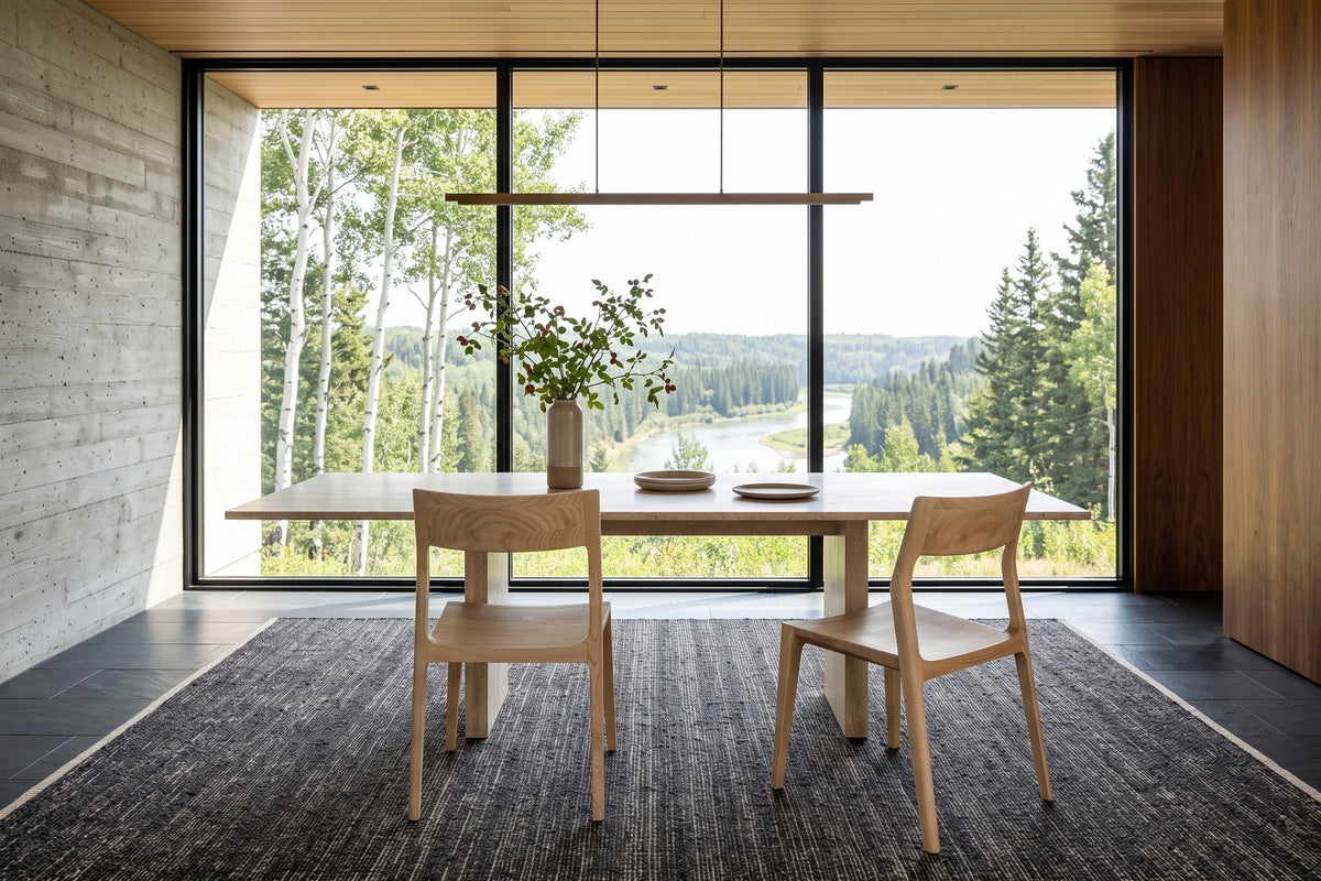 Two Cison dining chairs in Natural seen from behind at a travertine table in an Edmonton river valley house