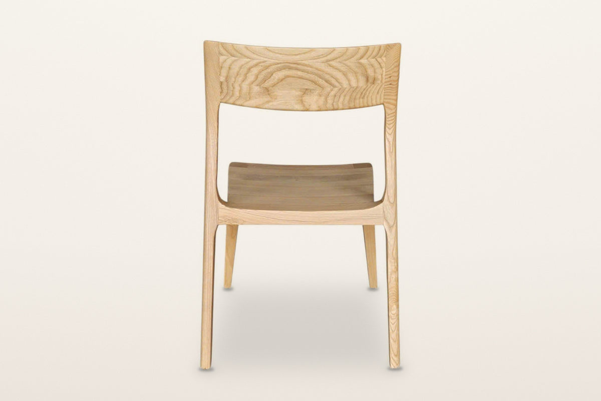 Cison dining chair in Natural, back view on a warm white studio backdrop: the backrest panel and the two posts