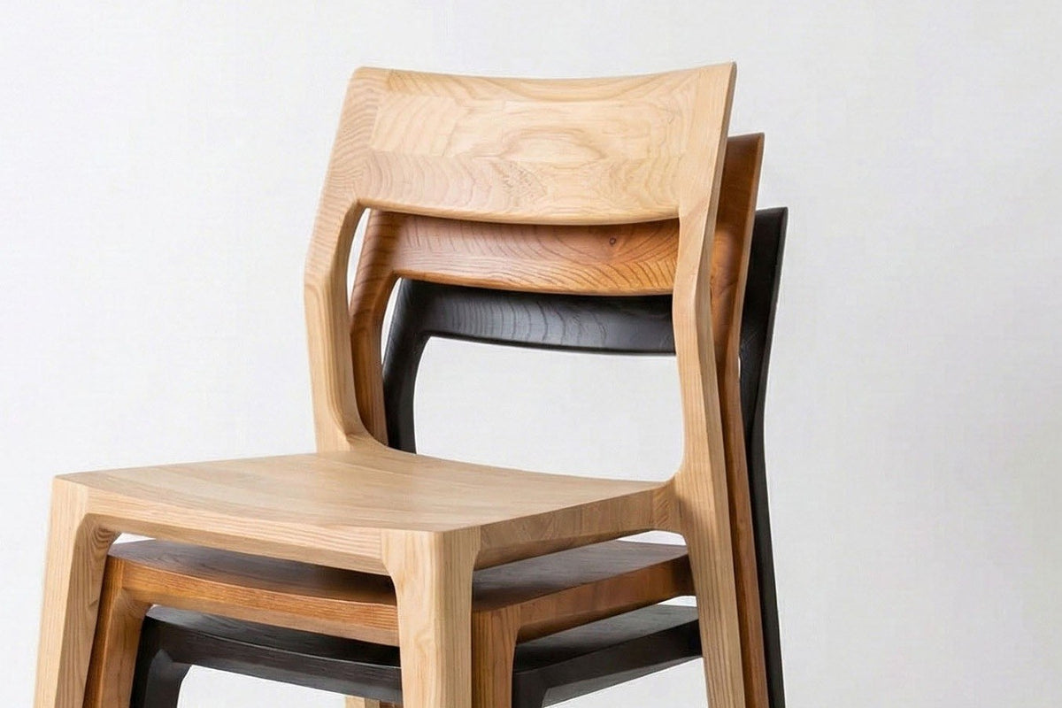 Three Cison dining chairs stacked, in Natural, Warm Brown and Black: the backrests and seats nest one over the other