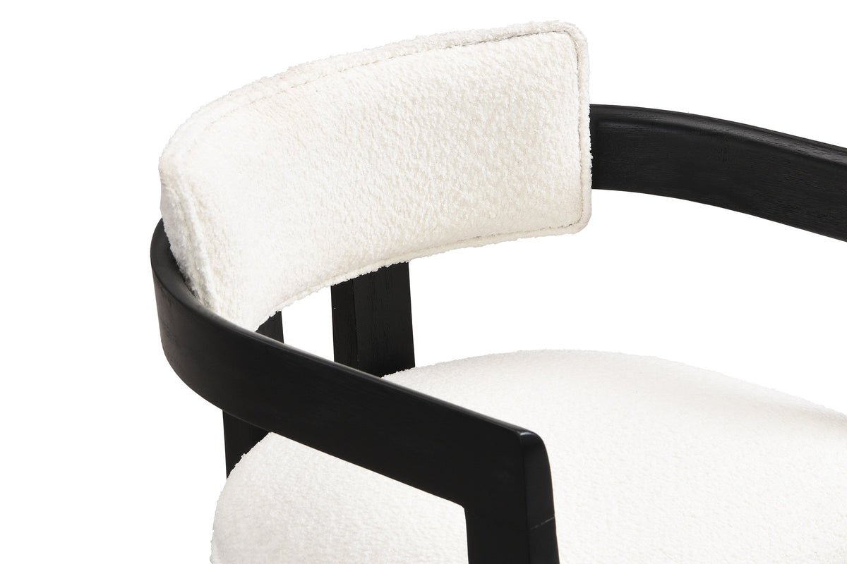 Close-up of the flat black arm rail curving round behind the slim ivory boucle back pad of the Cisternino chair