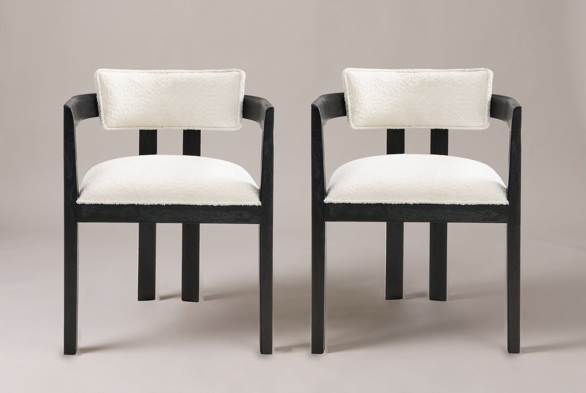 A set of two Cisternino dining armchairs in Black with ivory boucle seats, straight front view on a studio backdrop