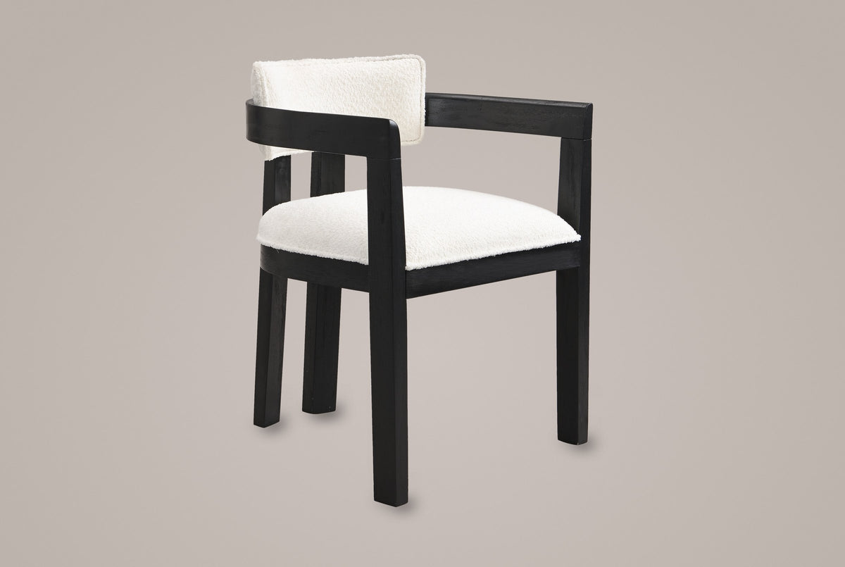 Cisternino dining armchair in Black with an ivory boucle seat, three-quarter view on a warm grey studio backdrop