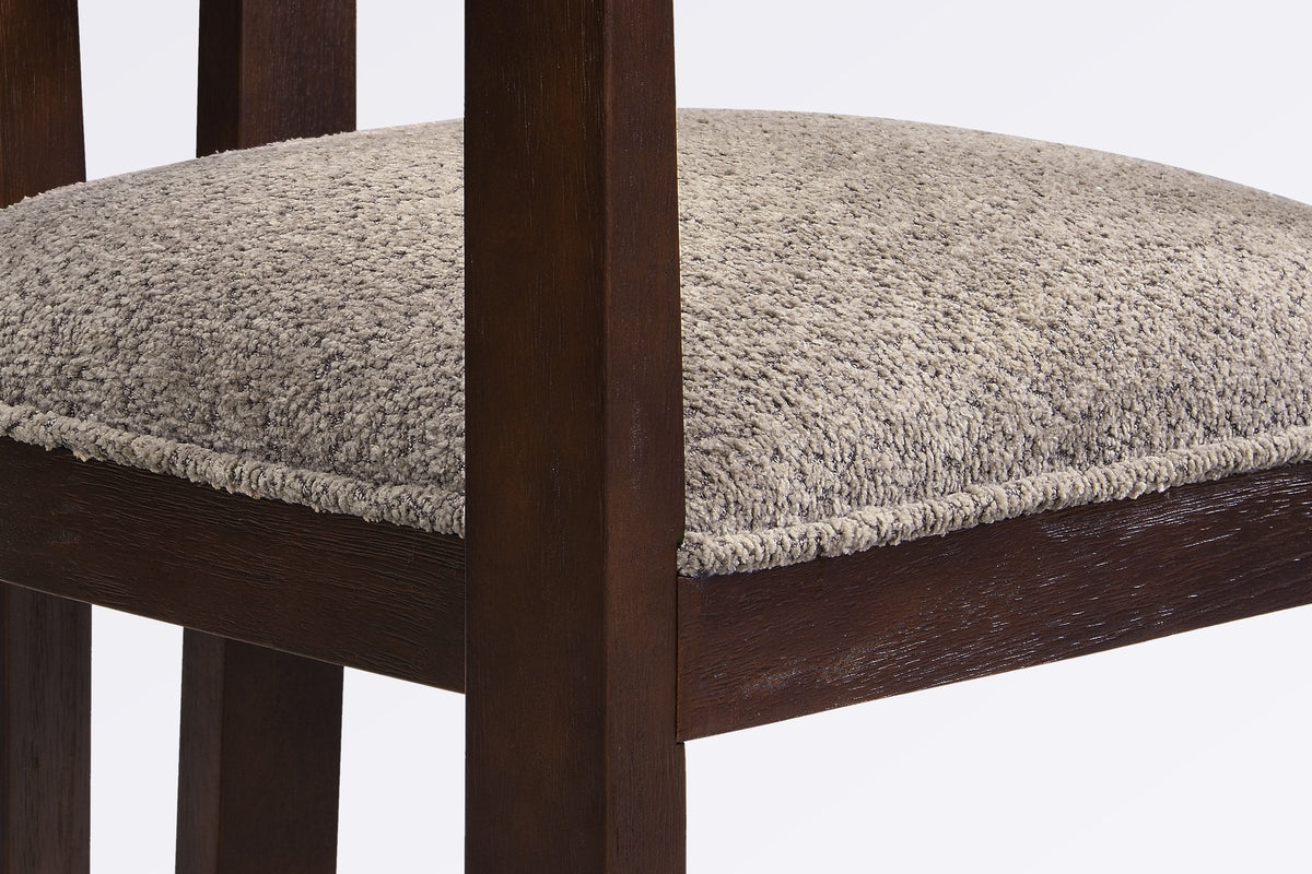 Close-up of the light brown boucle seat, the square front leg and the espresso wire-brushed wood frame of the Cisternino chai
