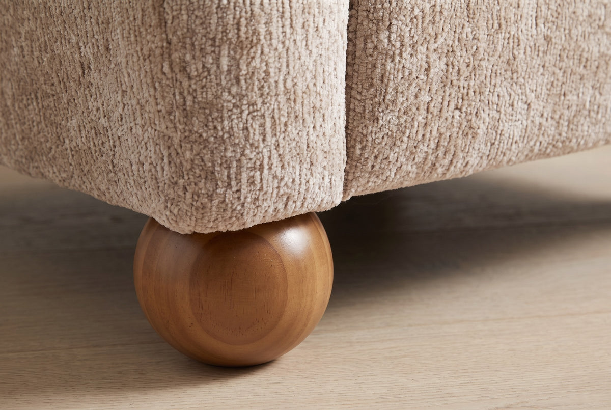 Close-up of a solid wood ball foot under the chenille corner of the Collodi chair