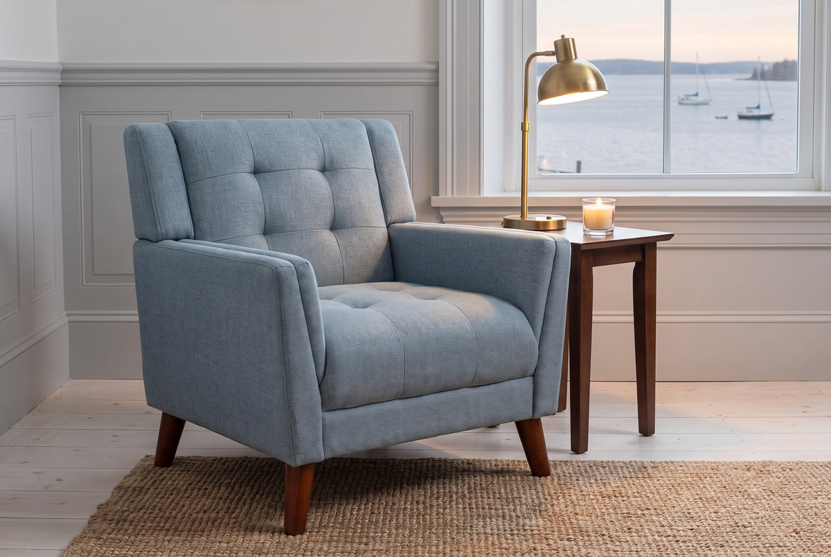 Comacchio armchair by a harbour window at dusk, a brass lamp lit on a walnut side table