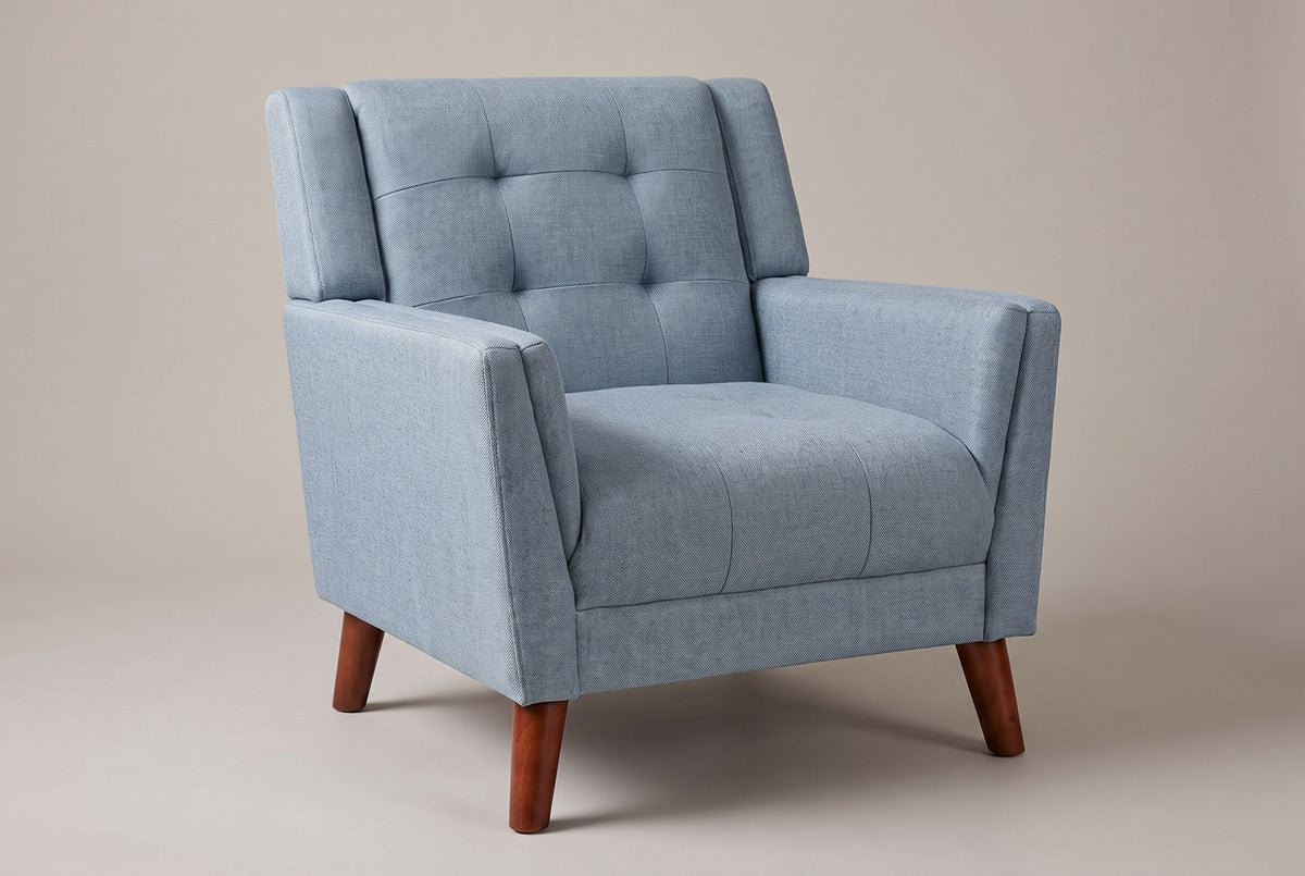Comacchio tufted mid-century armchair in blue, three-quarter view on a warm grey studio backdrop