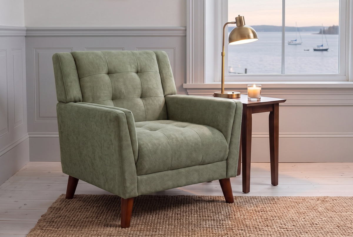 Comacchio armchair in green by a harbour window at dusk, a brass lamp lit on a walnut side table