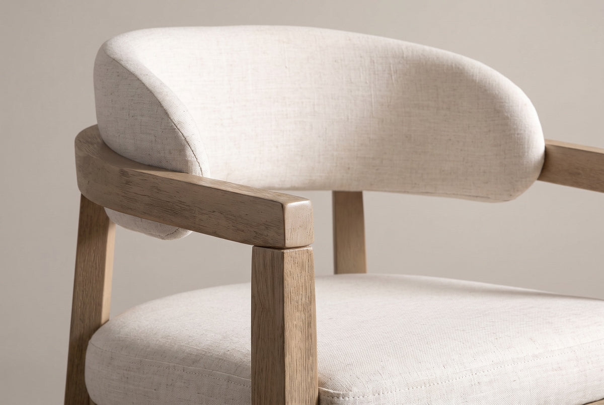 Close-up of the padded linen-look back, the curved wooden rail and the wooden arm of the Corinaldo dining chair
