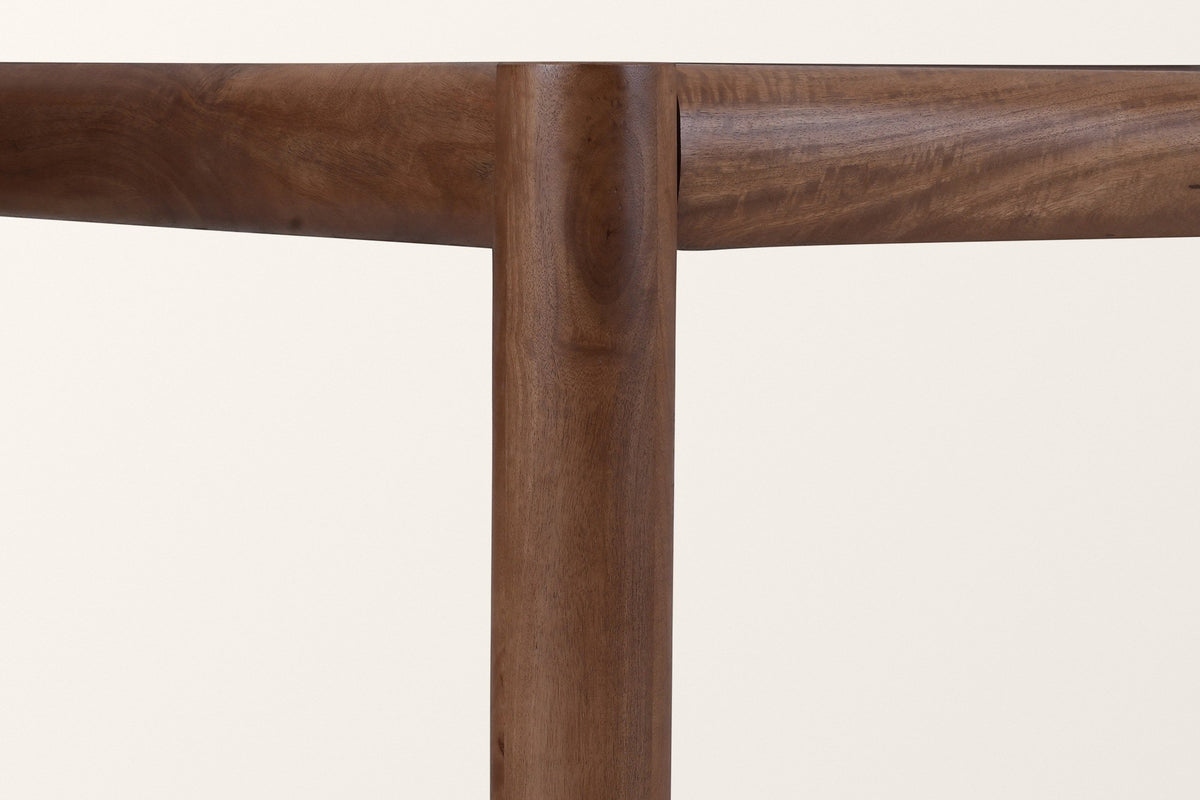 Close-up of a Corniglia leg in walnut where two round rails meet it under the top