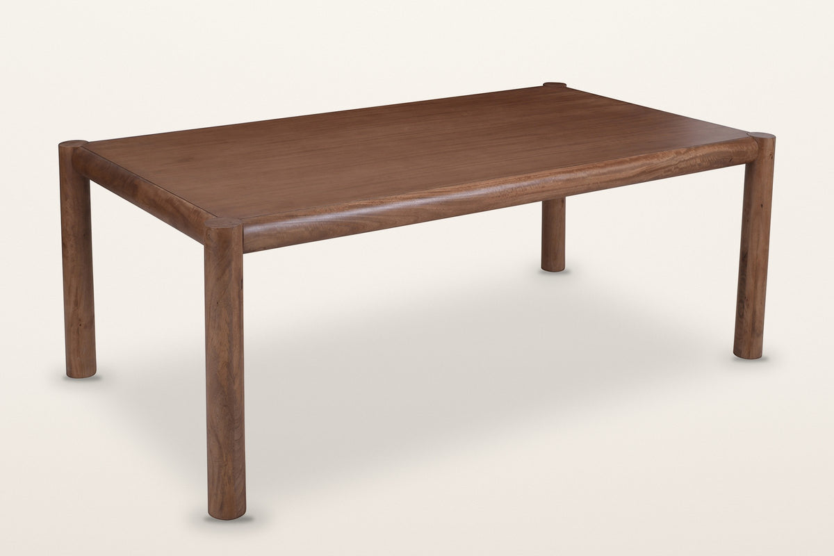 Corniglia mango wood dining table in walnut, three-quarter view on a warm white studio backdrop