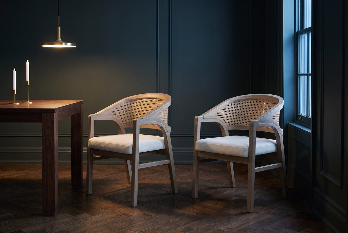 A pair of Cortina cane-back dining chairs in a dark green Toronto dining room at dusk beside a walnut table and a brass penda