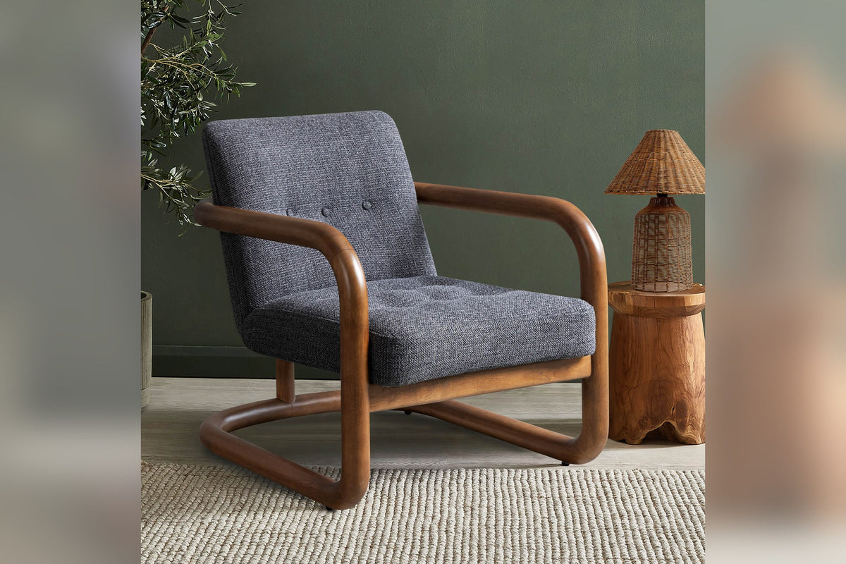 Corwin Charcoal accent chair against a deep green wall beside a woven lamp