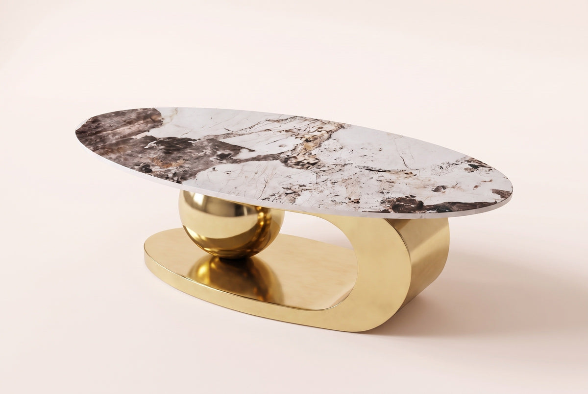 The Cosima coffee table from a higher angle at the sphere end, showing the veined oval top above the gold sphere and loop