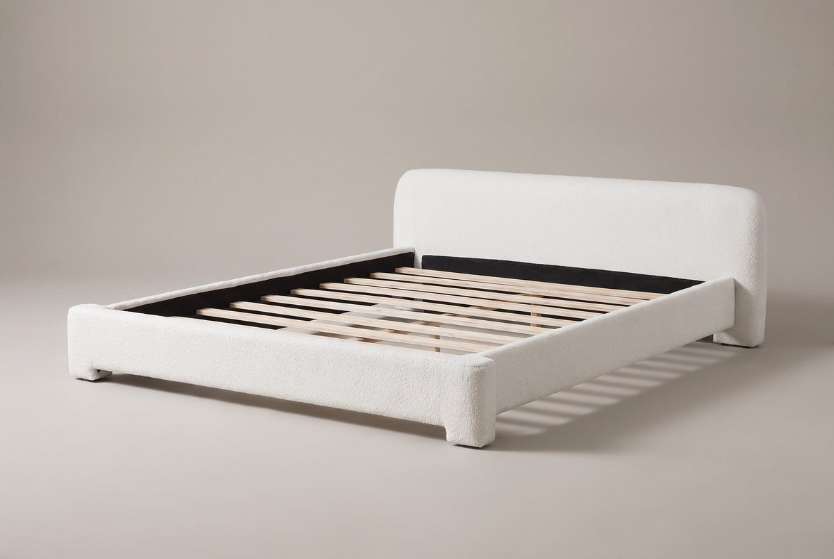Cupello boucle platform bed in white, three-quarter view of the bare frame on a warm grey studio backdrop