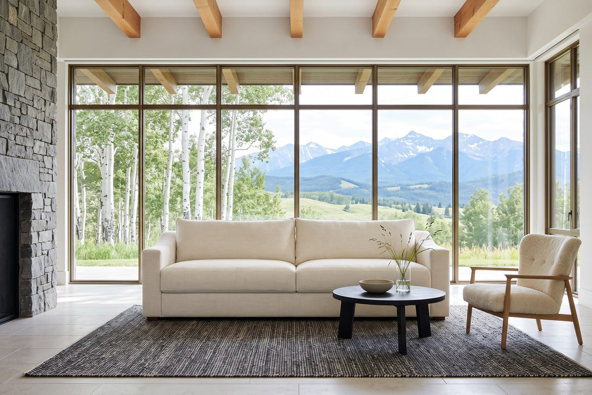 Cupramontana sofa in Beige facing a round black table in a Millarville ranch house, a fieldstone fireplace