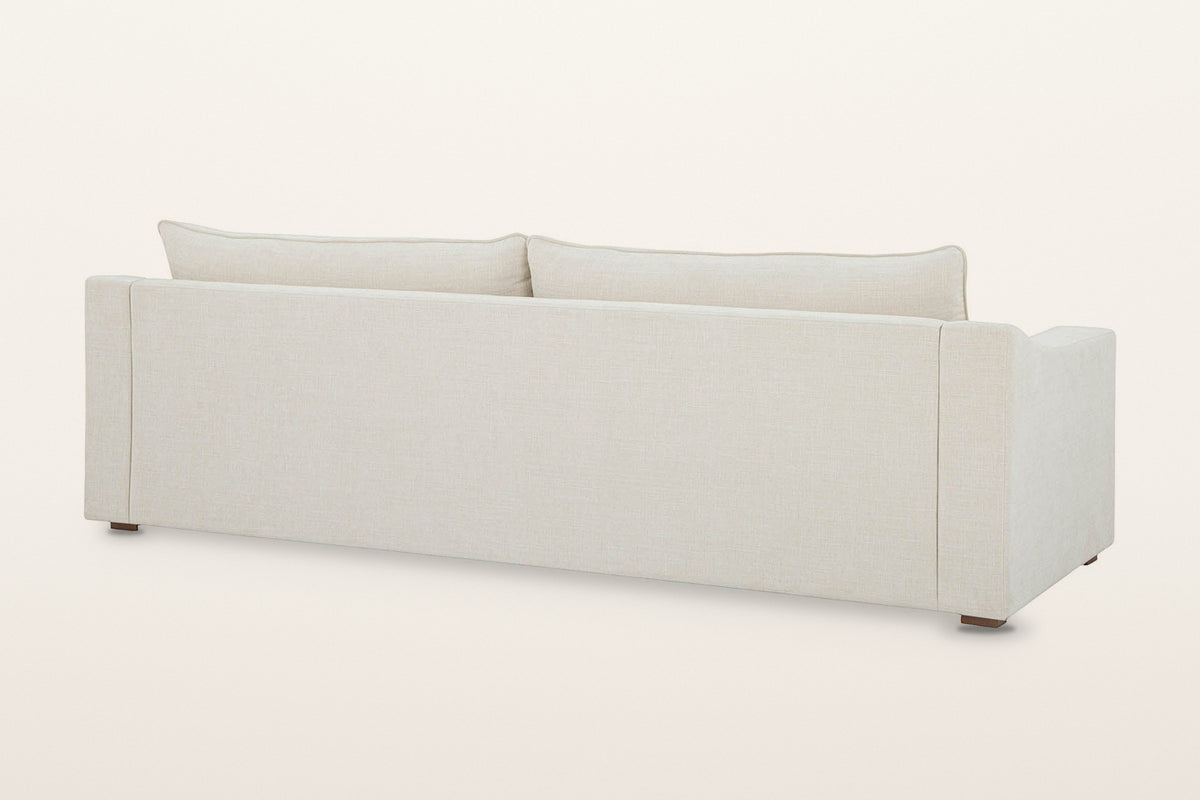 Back of the Cupramontana sofa in Beige on a warm white studio backdrop: a plain upholstered back panel with the back cushions