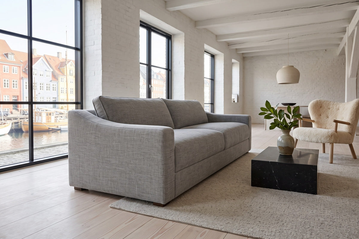 Cupramontana sofa in Grey seen low from the front right in a Copenhagen harbour loft, whitewashed brick