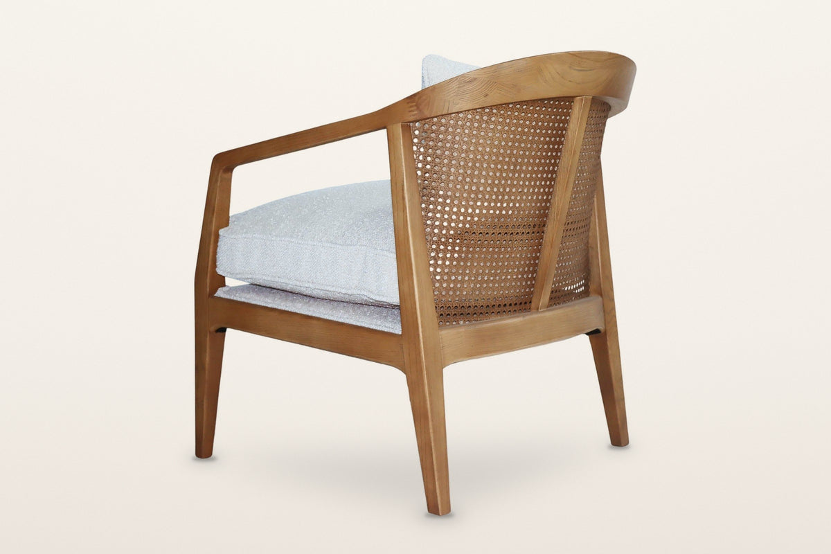 Esanatoglia accent chair from the rear three-quarter on a warm white studio backdrop: the curved open cane back with one cent