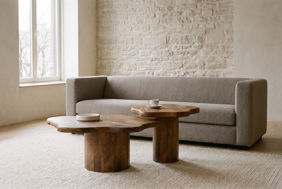 Exilles walnut cloud coffee tables in front of a stone-grey boucle sofa in an Old Montreal loft with a limewashed stone wall
