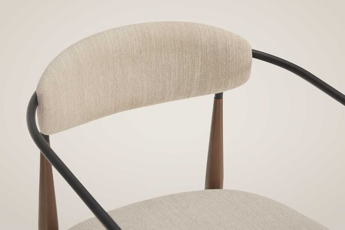 Close-up of the oval back pad, the black steel rail curving behind it and the bronze legs