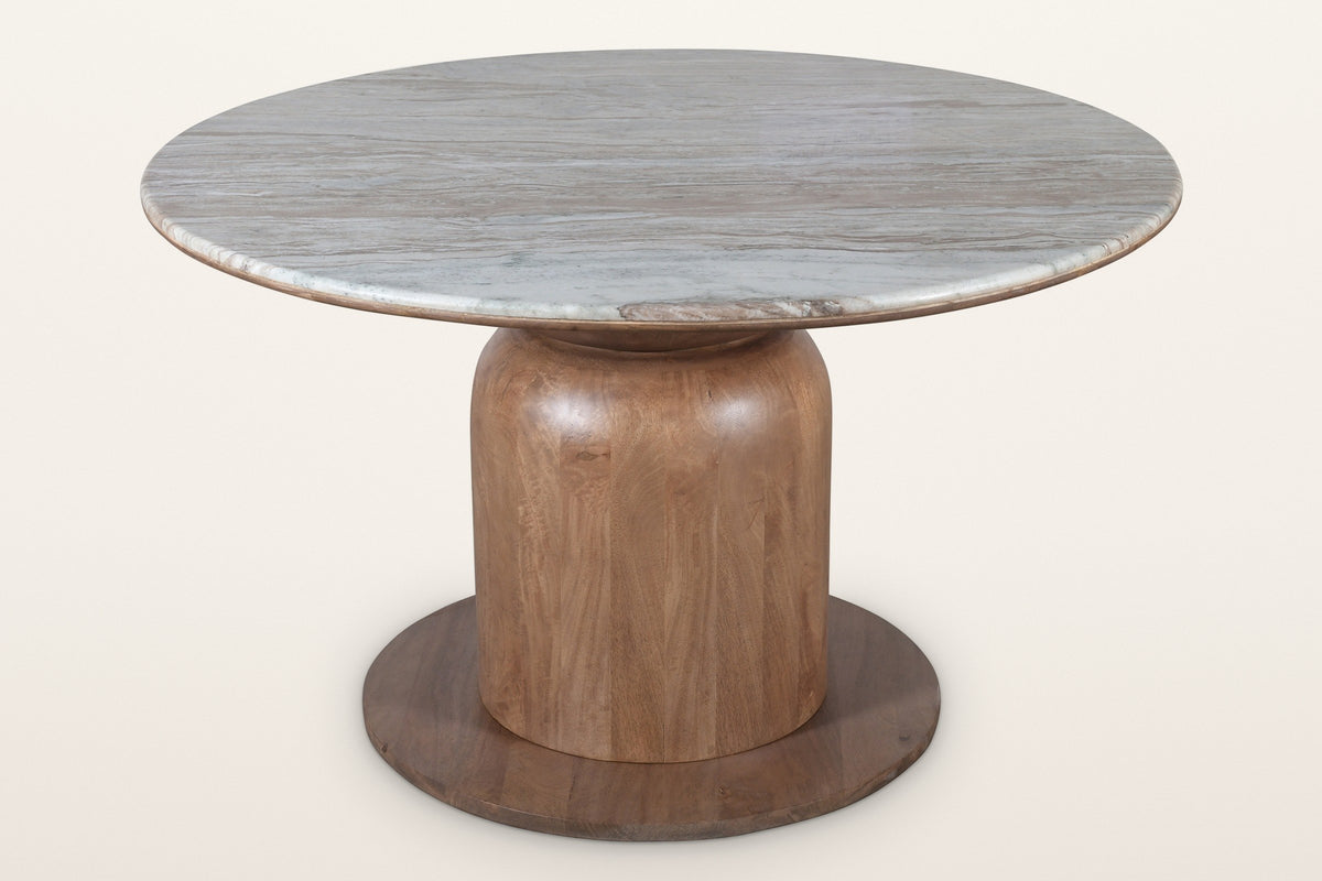 Fiumalbo round marble pedestal dining table, three-quarter view on a warm white studio backdrop: a Fantasy Brown marble top o