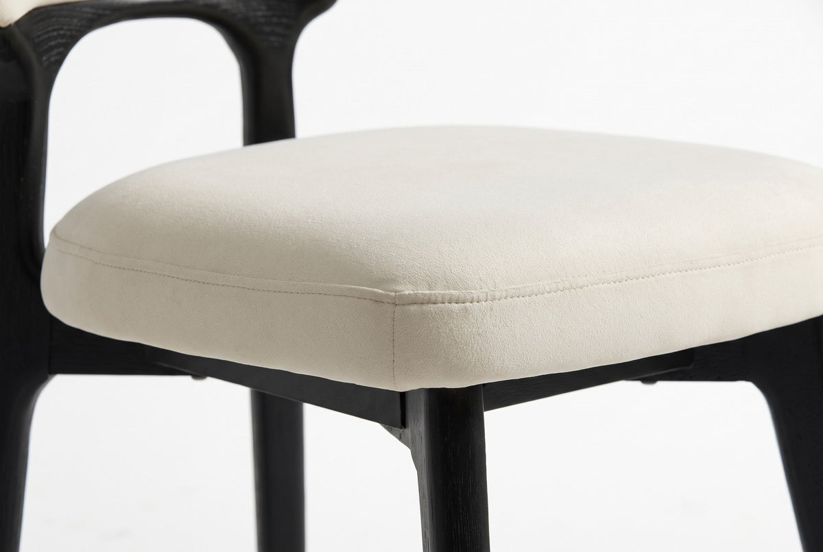 Close-up of the Fosdinovo thick cream seat cushion with its stitched edge seam above the black wood seat frame and leg