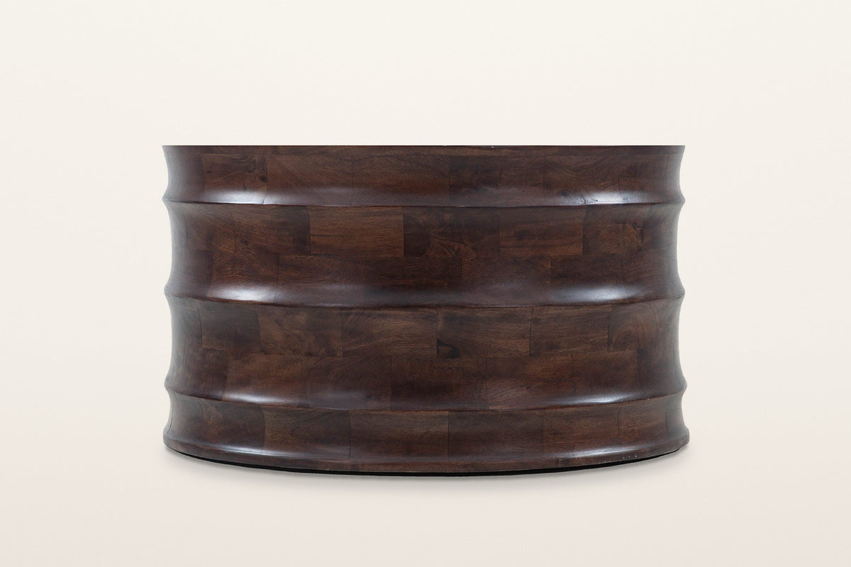 Gangi coffee table in Walnut, straight side view on a warm white studio backdrop: four curved bands meeting at three rounded