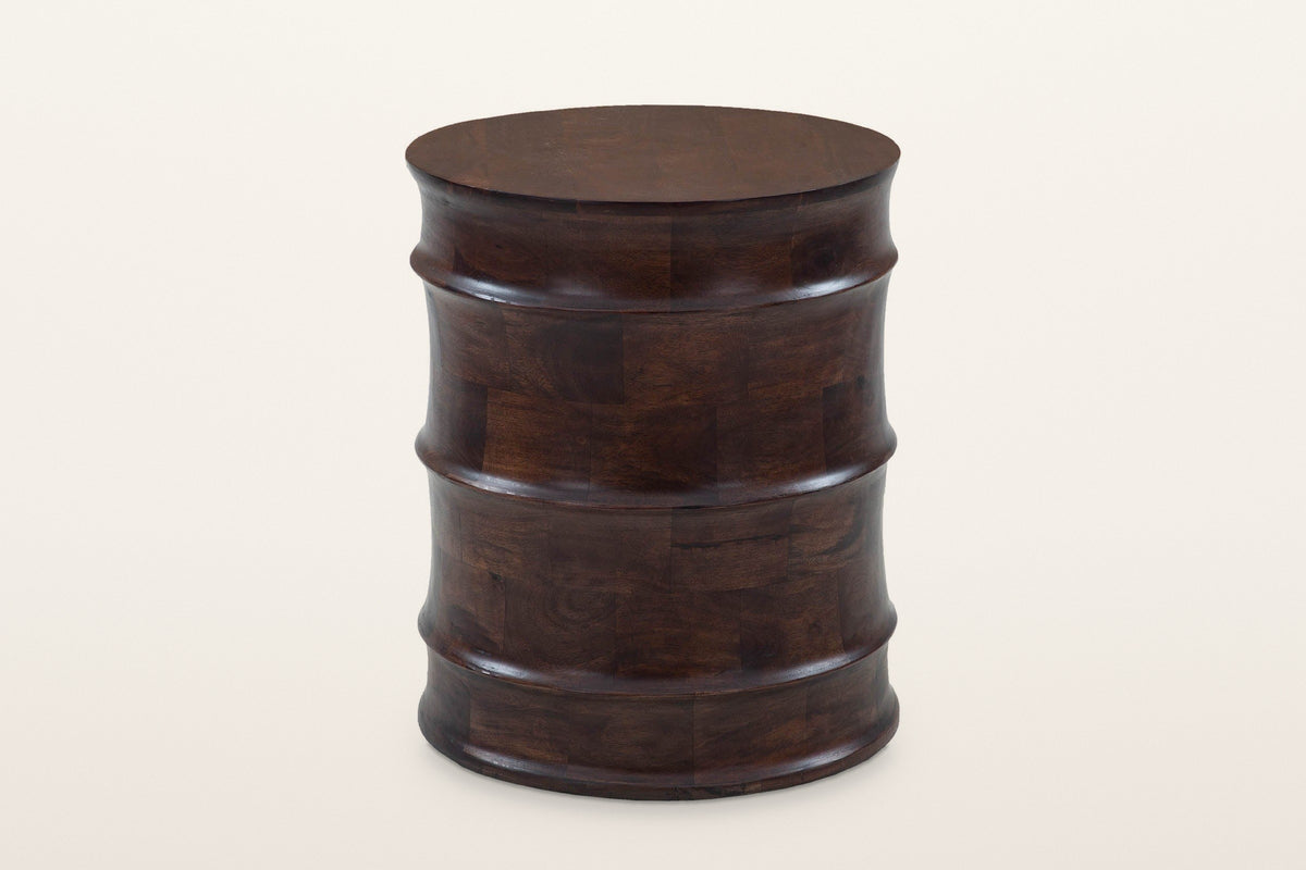 Gangi solid mango side table in Walnut, three-quarter view on a warm white studio backdrop: a round drum of four curved bands
