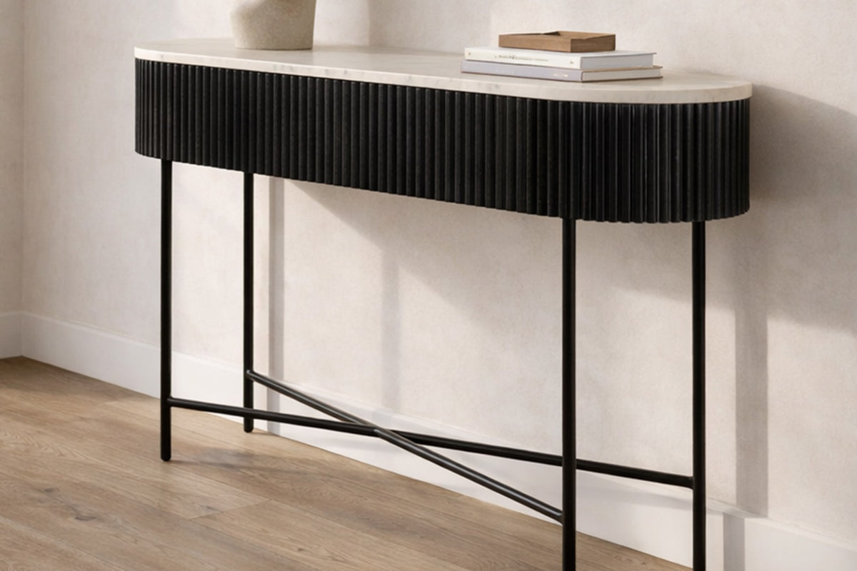 Gideon black reeded console table with white marble top against a hallway wall