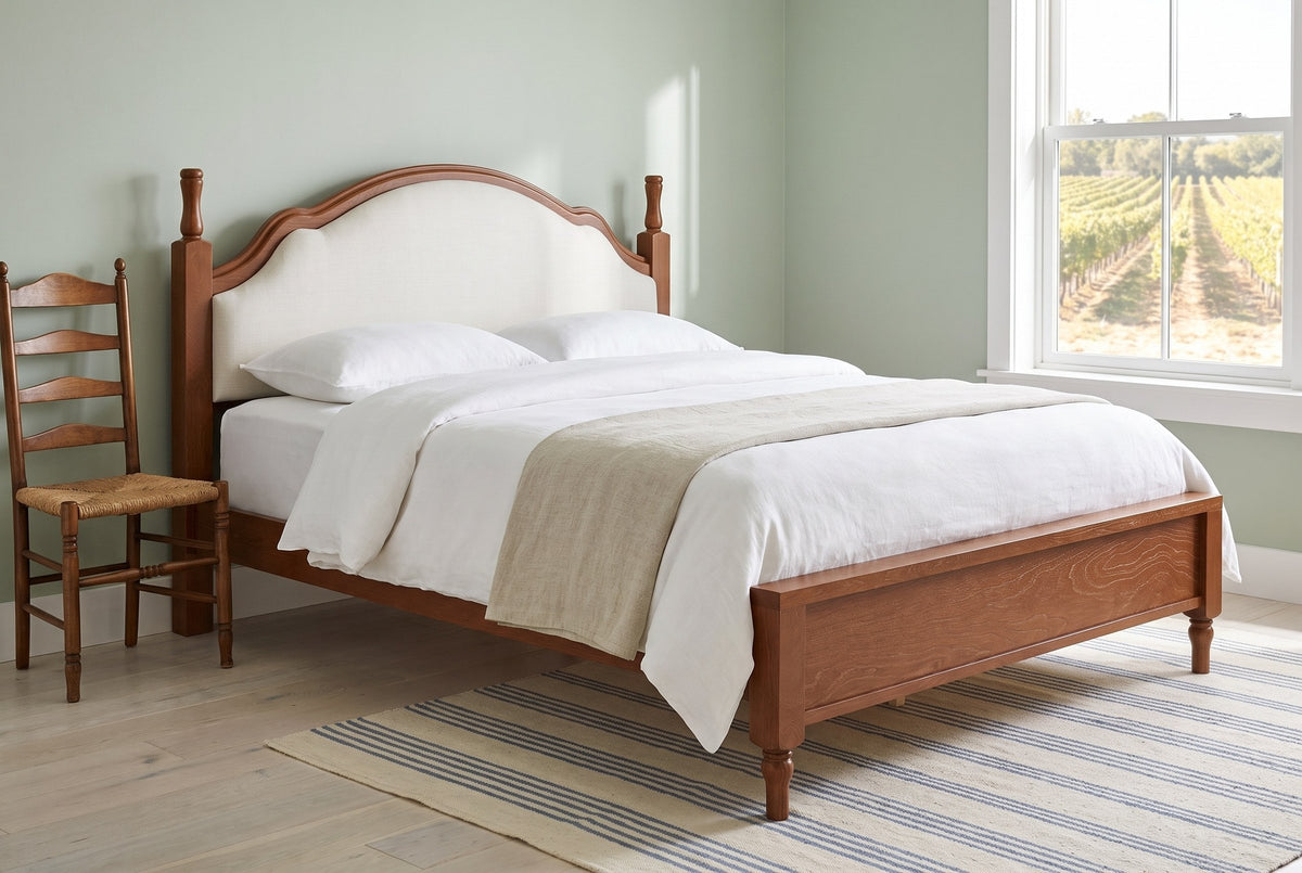 Gradara bed in a sage-green guest room with a striped rug, a rush-seat ladder-back chair and a window onto a vineyard