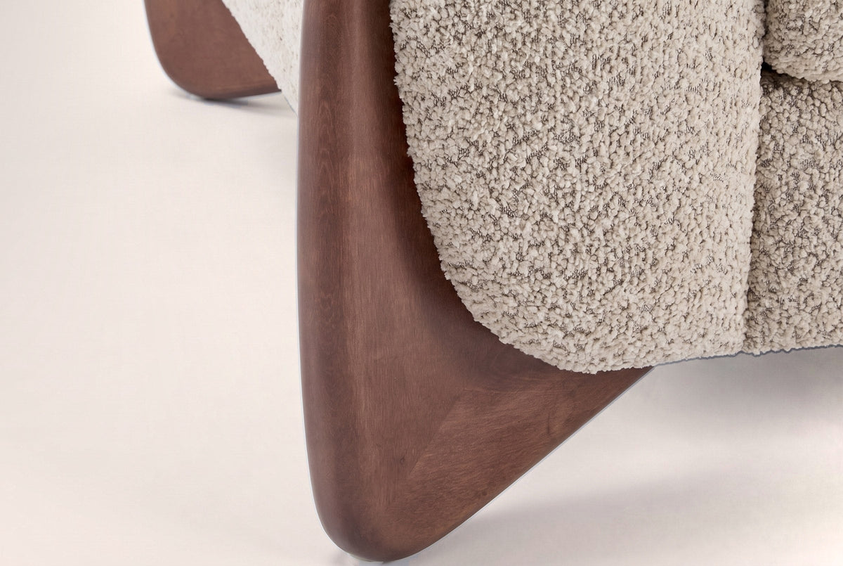 Close-up of a solid birch wedge leg in a walnut-brown stain under the boucle arm