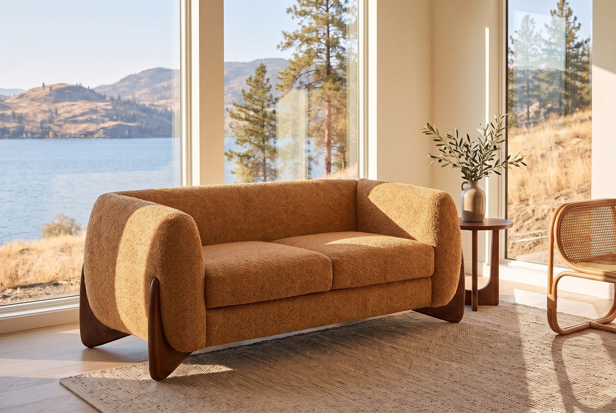 Greccio boucle loveseat in caramel in a lake house living room with a lake and golden hills behind the windows