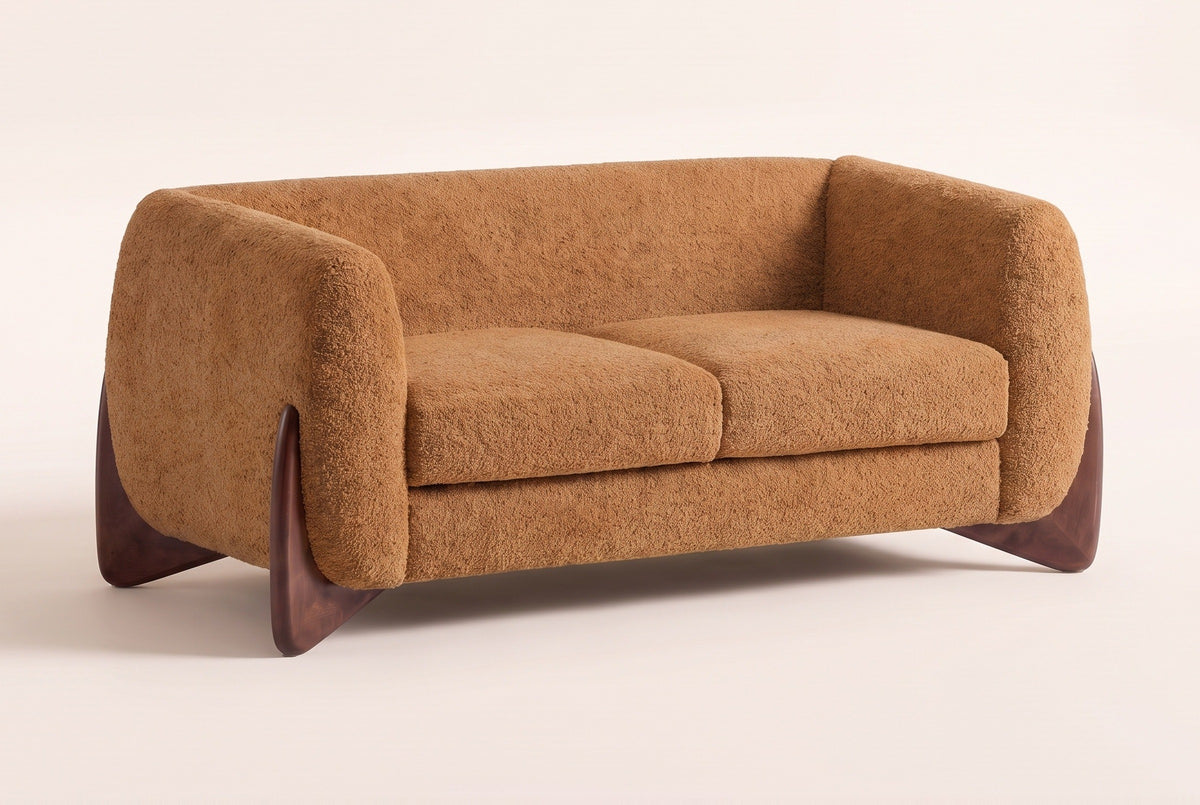 Greccio boucle loveseat in caramel, three-quarter view on a warm cream studio backdrop