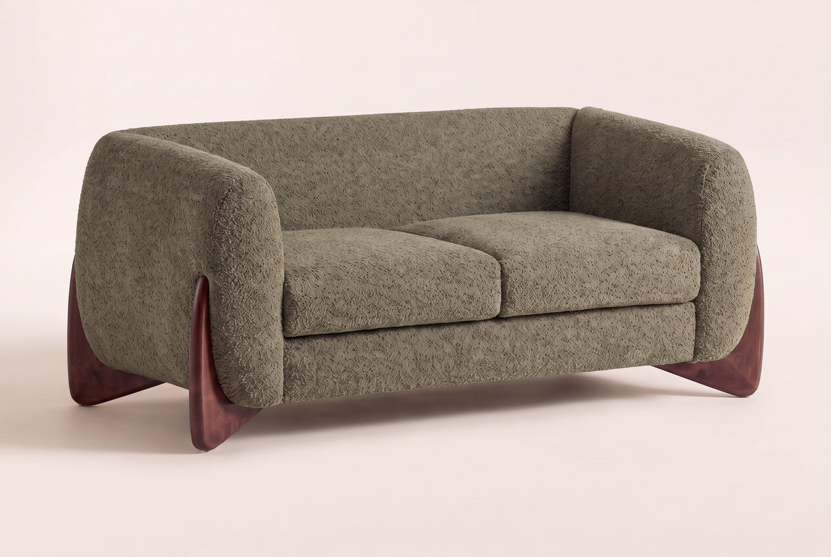 Greccio boucle loveseat in olive green, three-quarter view on a warm cream studio backdrop