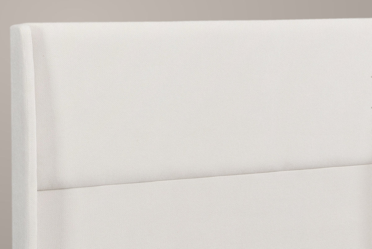 Close-up of the Greve headboard: the rounded top of a wing, the fine beige chenille weave and the one channel line