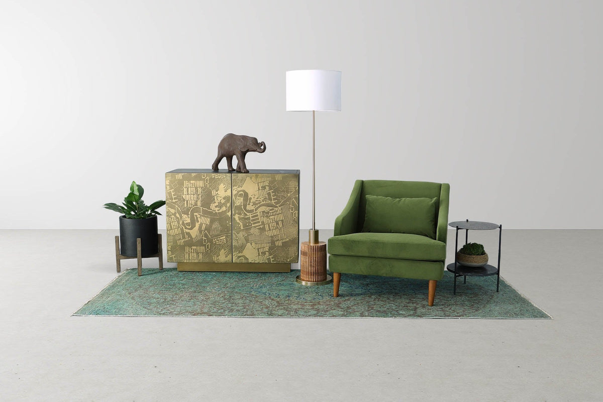 Hadrian floor lamp between a brass-clad cabinet and a green armchair