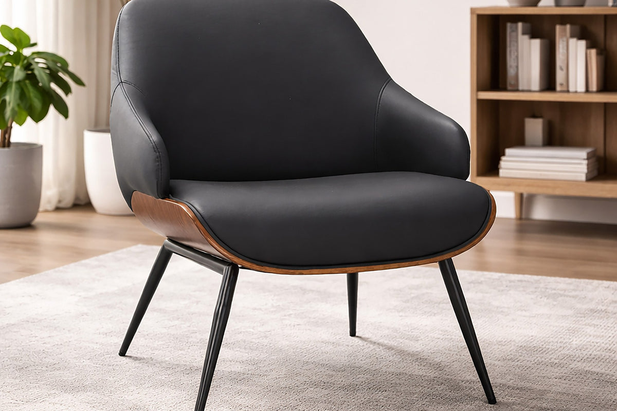 Iver black faux leather accent chair on a rug in a living room with a bookshelf