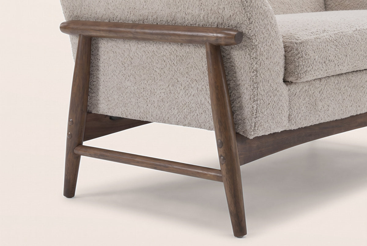 Close-up of the wooden side frame: a round arm rail, two splayed tapered legs, a low stretcher and bolt caps
