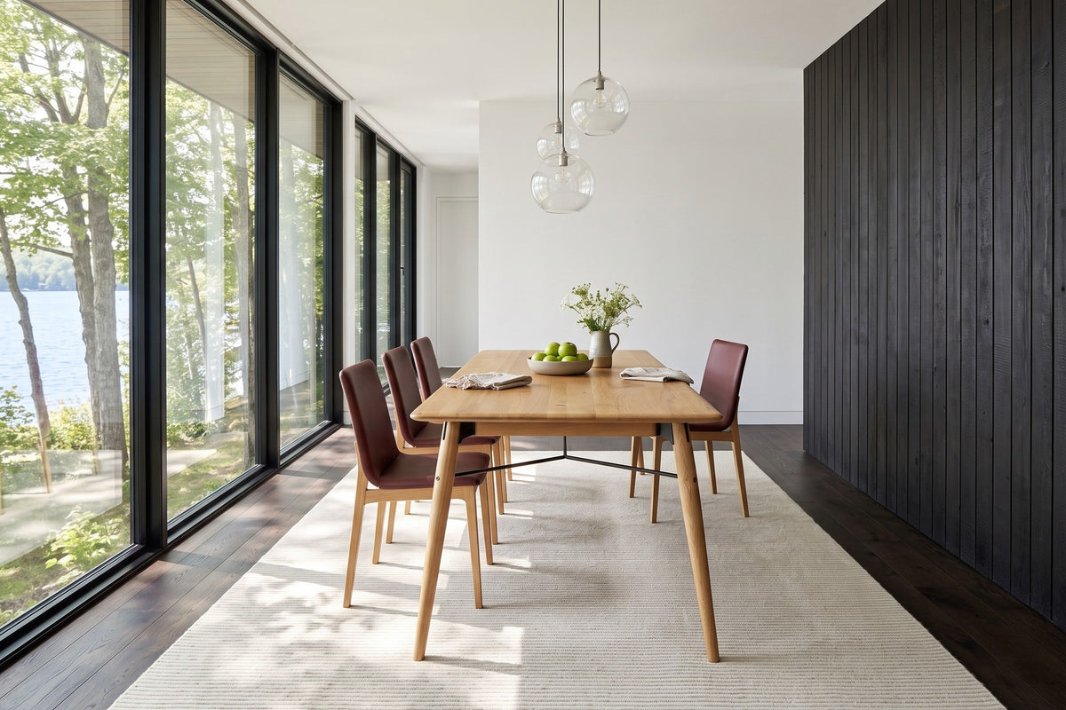 End view of the Larino dining table in Natural in a Tremblant lake house, with a charred cedar wall