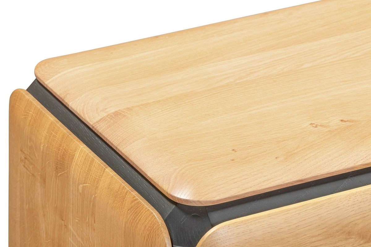 Close-up of the Larino corner in Natural and Black: the softly rounded oak top over the thin black band and a rounded oak doo