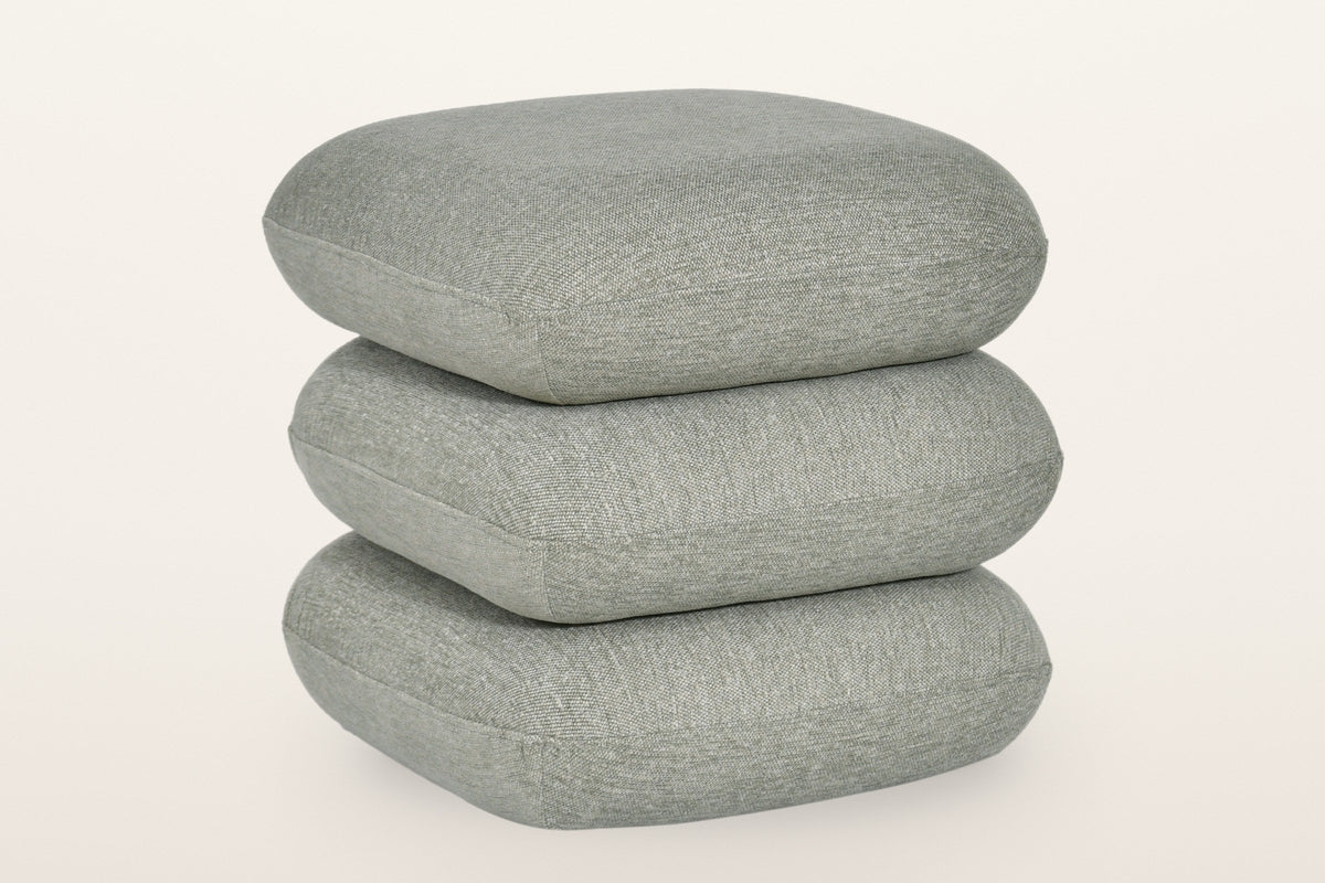 Lavagna square ottoman in Sage, three-quarter view on a warm white studio backdrop: three soft square pillows stacked