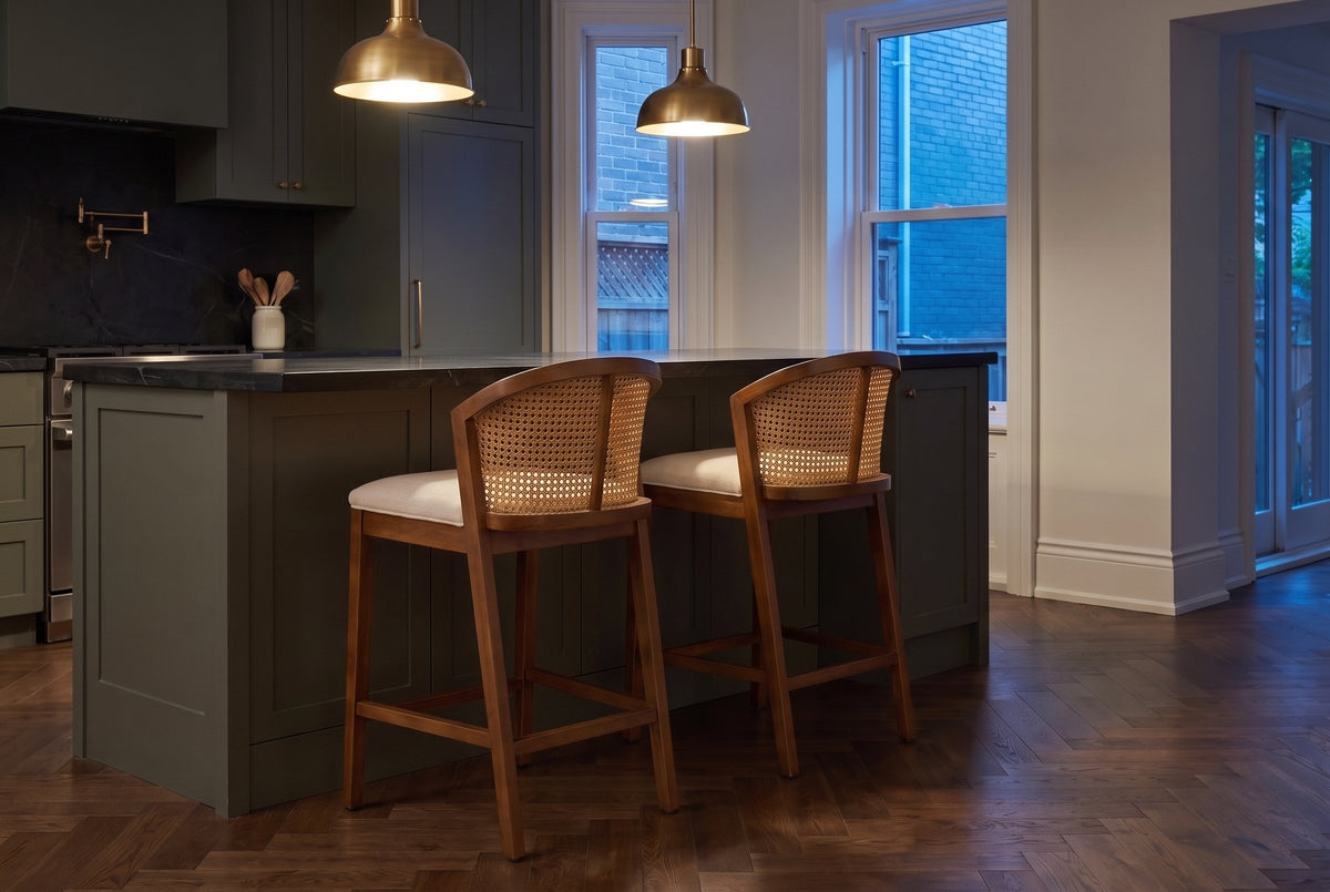 Two Lazise counter stools in the Walnut finish at a dark green island under brass pendant lights in a Toronto kitchen at dusk