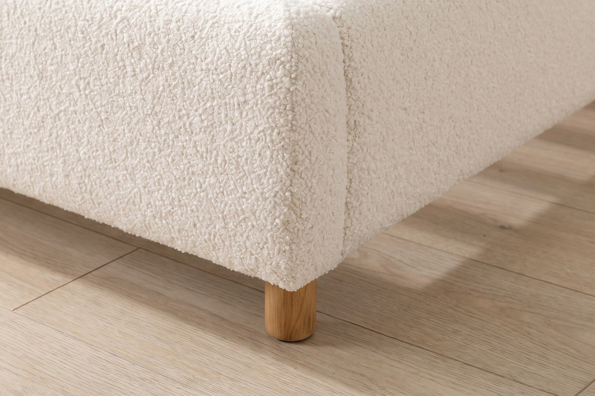 Close-up of the rounded foot corner of the boucle rails on a round natural wood foot