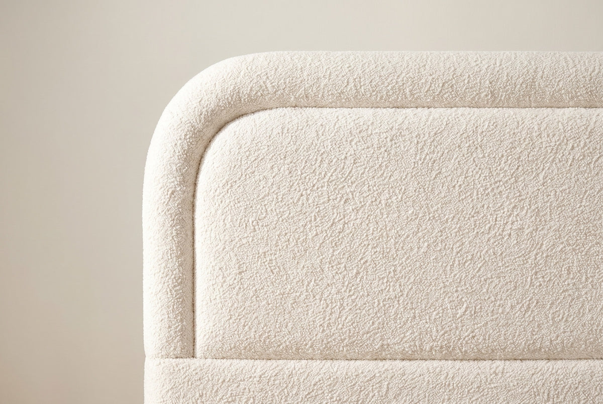 Close-up of the rounded headboard corner: a raised boucle border around the inset panel