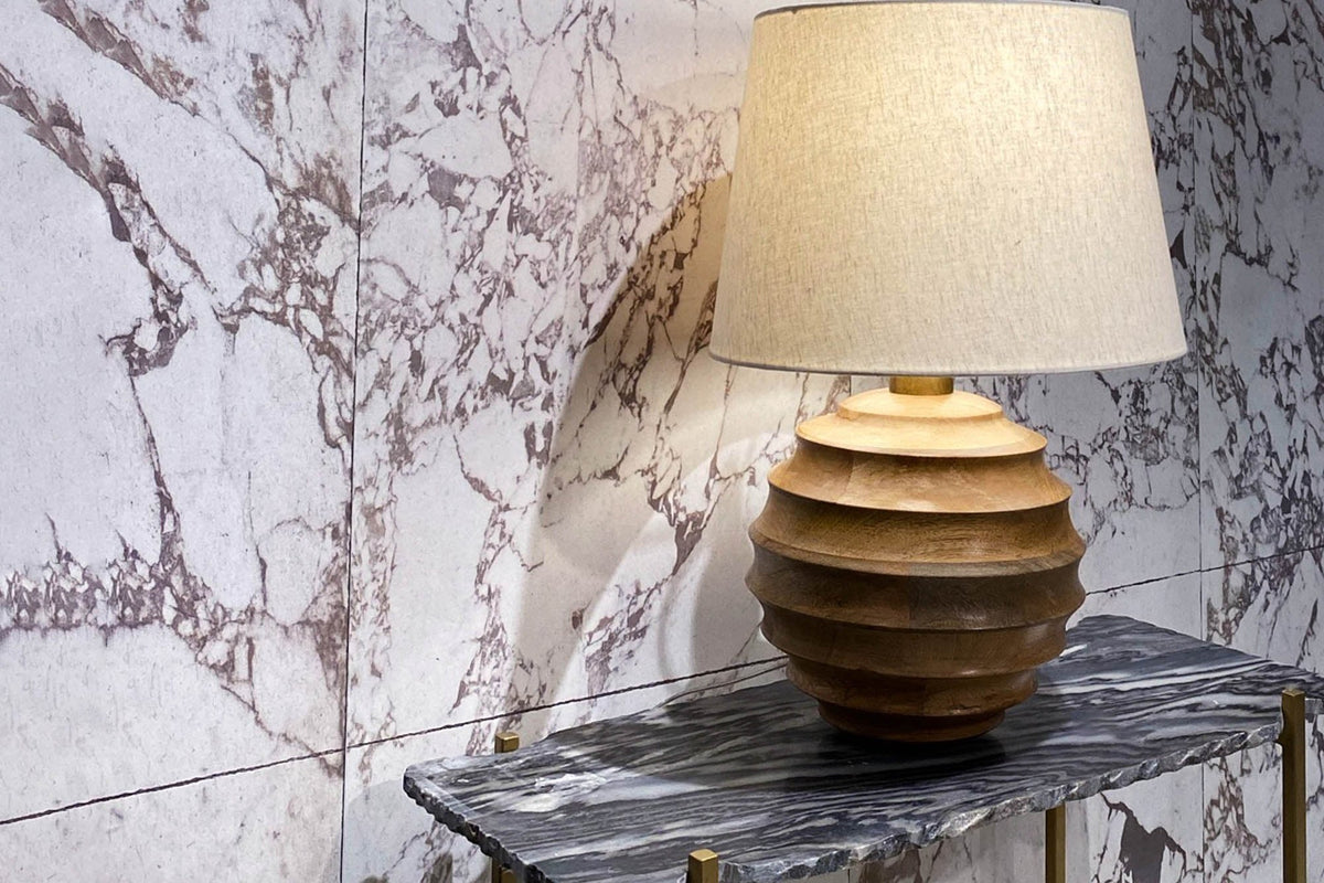 Linden mango wood lamp on a marble console against a veined stone wall