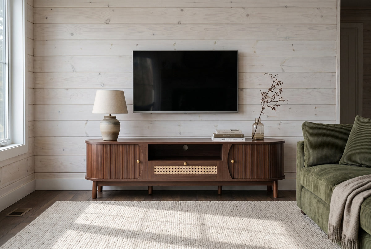 The Livia media console in Natural Walnut below a switched-off TV, against whitewashed pine boards, beside a moss green corduroy sofa
