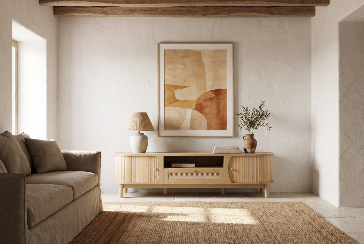 The Livia media console in Natural below a large sand and terracotta painting, in a lime-washed Ibiza finca with a beamed ceiling, a jute rug and a linen sofa