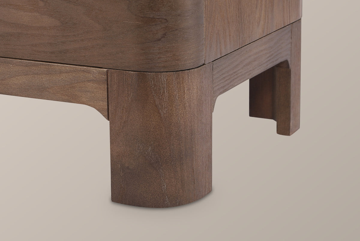 Close-up of a Lodi front leg in Brown Oak with its rounded face and the recessed apron meeting it in a curved cove